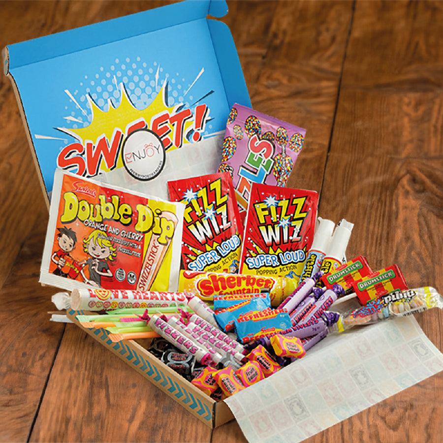 Retro sweets hamper letterbox gift penny post - laid out on a wooden surface. You can see classic sweets like Palma violets, fizzes, sherbert fountain, drumsticks, fruit salads & more.